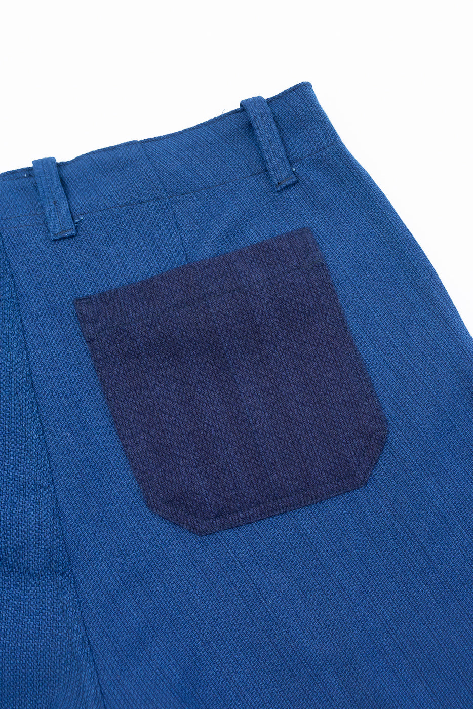Close-up of back pocket on blue selvedge pants, showcasing fabric texture and stitching detail.