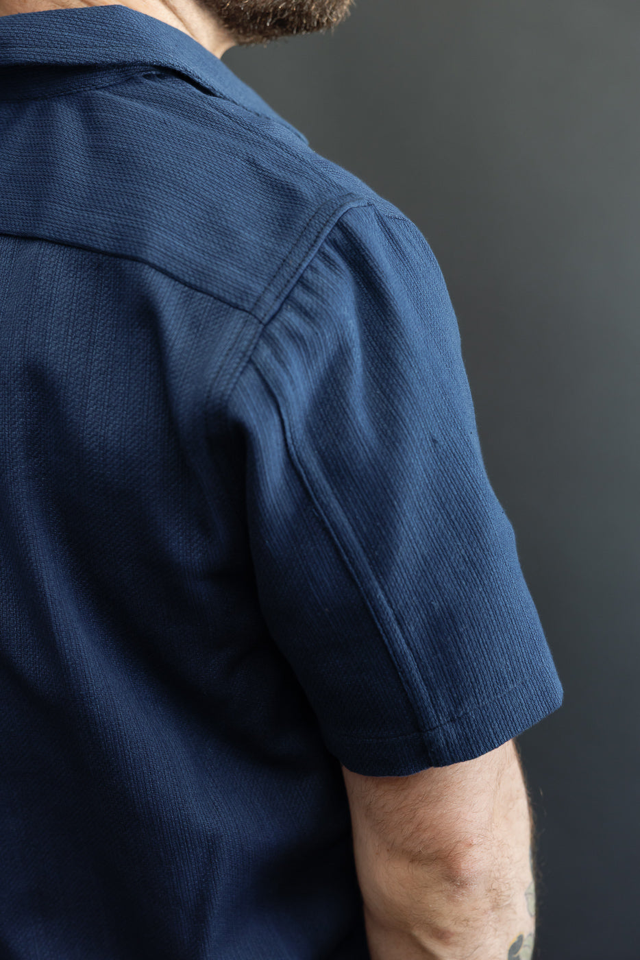 Close-up of navy shirt's back shoulder, worn by male model, 5'9