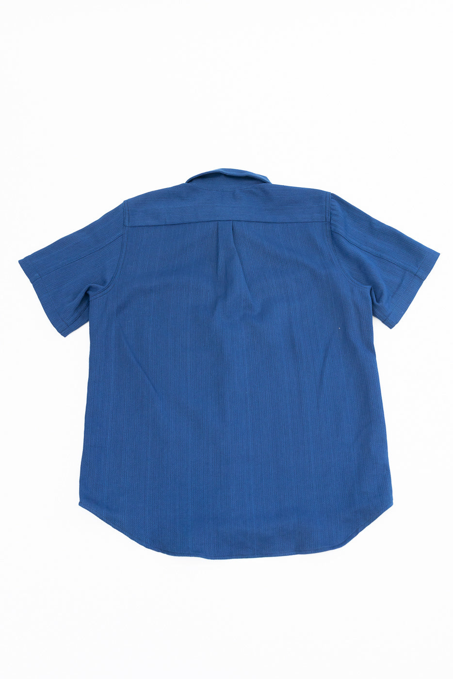 Back view of blue short-sleeve shirt, showing collar and hem details, flat lay