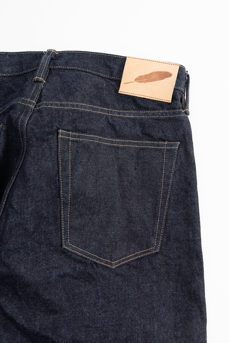 Dark blue jeans with a veg tab leather patch on a white background