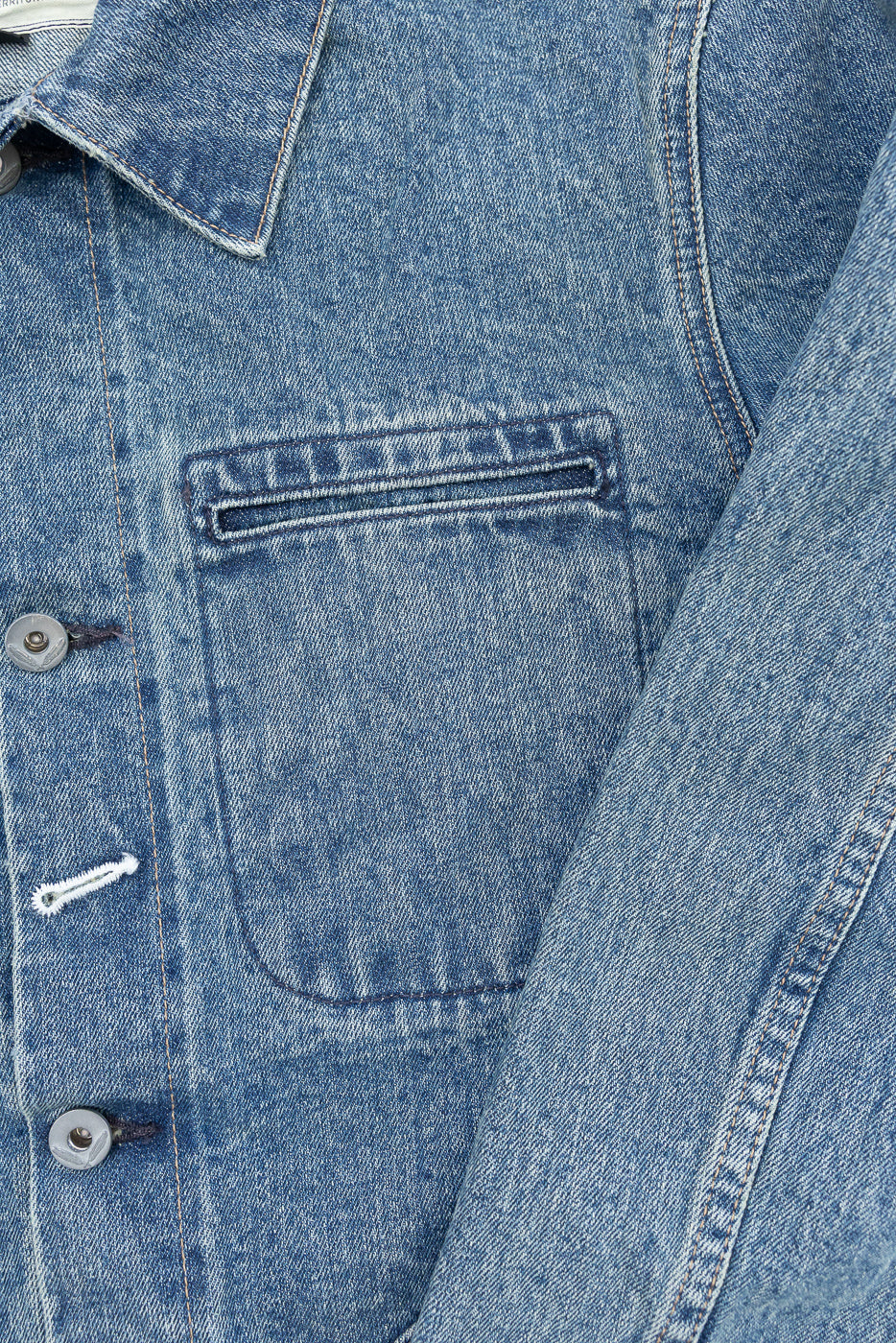 Close-up front of men's denim jacket showing chest pocket, buttons, and fabric texture