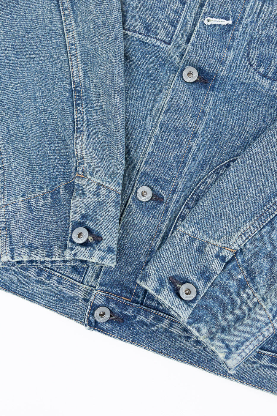 Close-up front view of men's denim jacket showing button details, fabric texture, and stitching on chest and sleeve