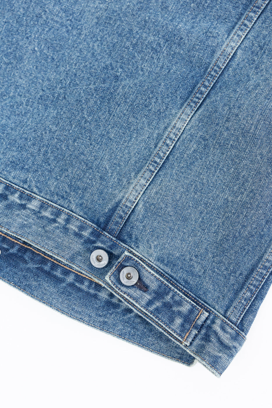 Close-up of front denim jacket hem with silver buttons and textured fabric
