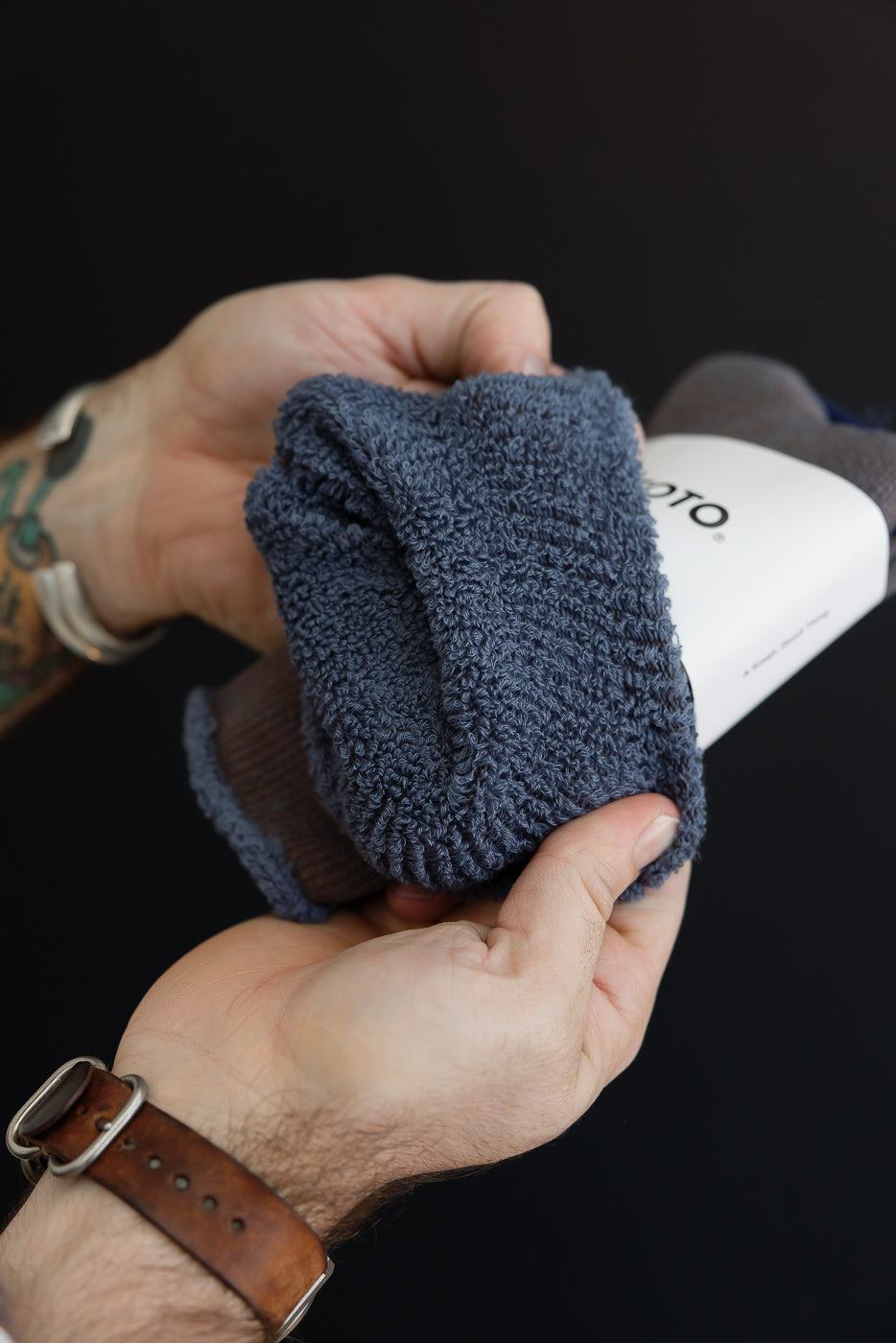 Close-up of hands feeling the thick, textured knit fabric of a blue sock.