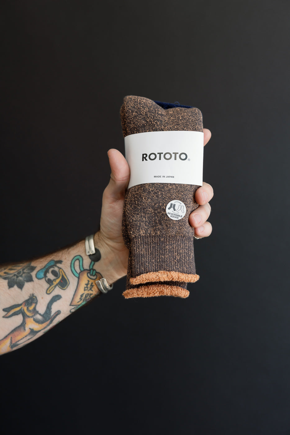 Close-up of the front of a pair of brown marled knit socks with a white ROTOTO band.