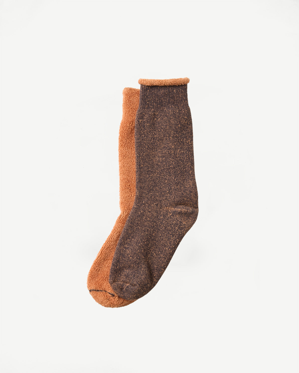 Close-up of a pair of thick, textured knit socks in orange and dark brown, shown from the side.