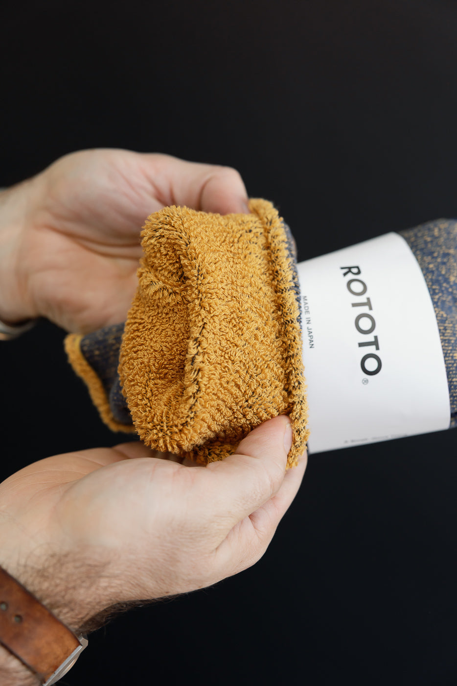 Close-up of the textured yellow microfiber towel being pulled from a white ROTOTO branded sleeve.