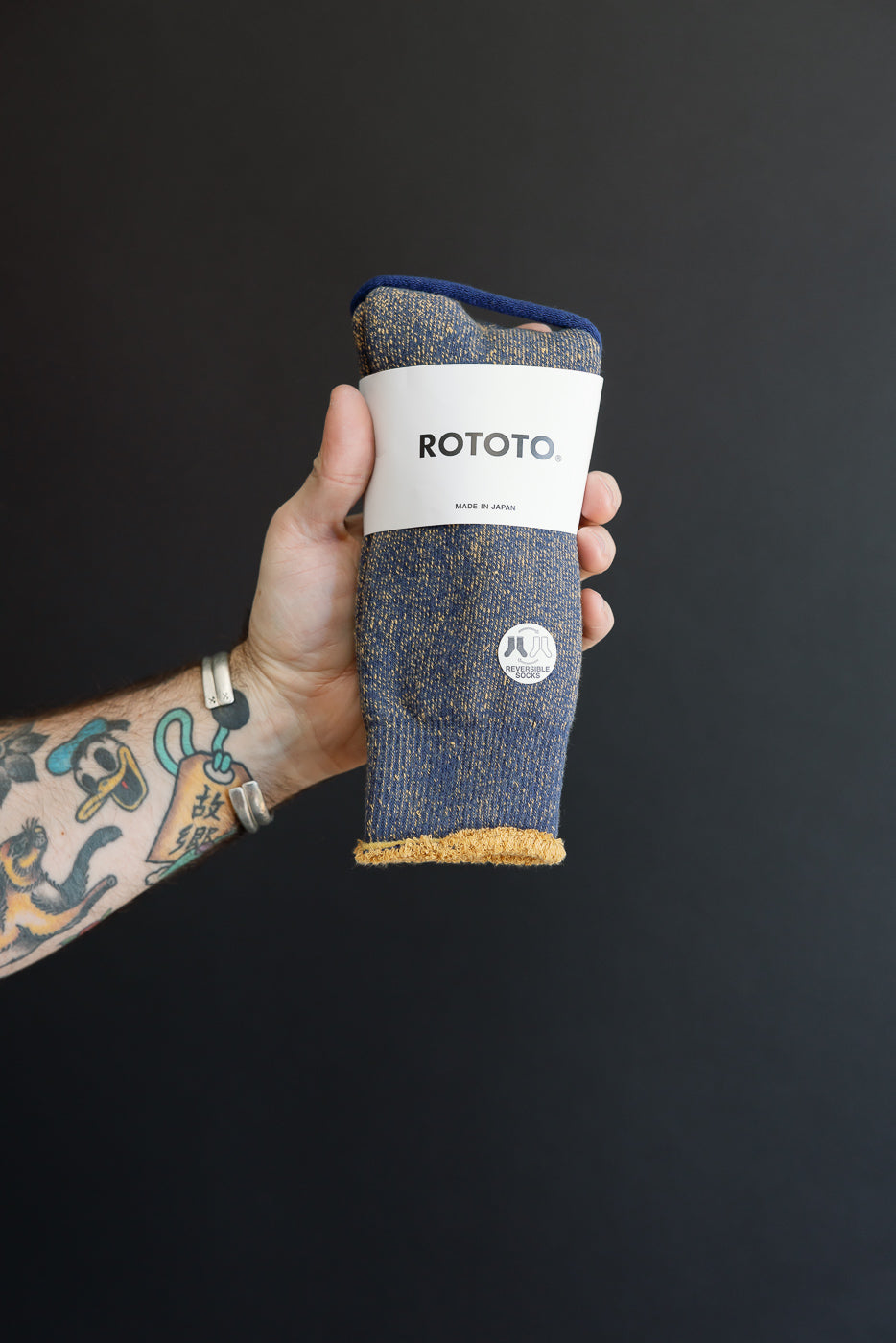 Close-up of the front of a pair of blue textured Rototo socks held in a hand.