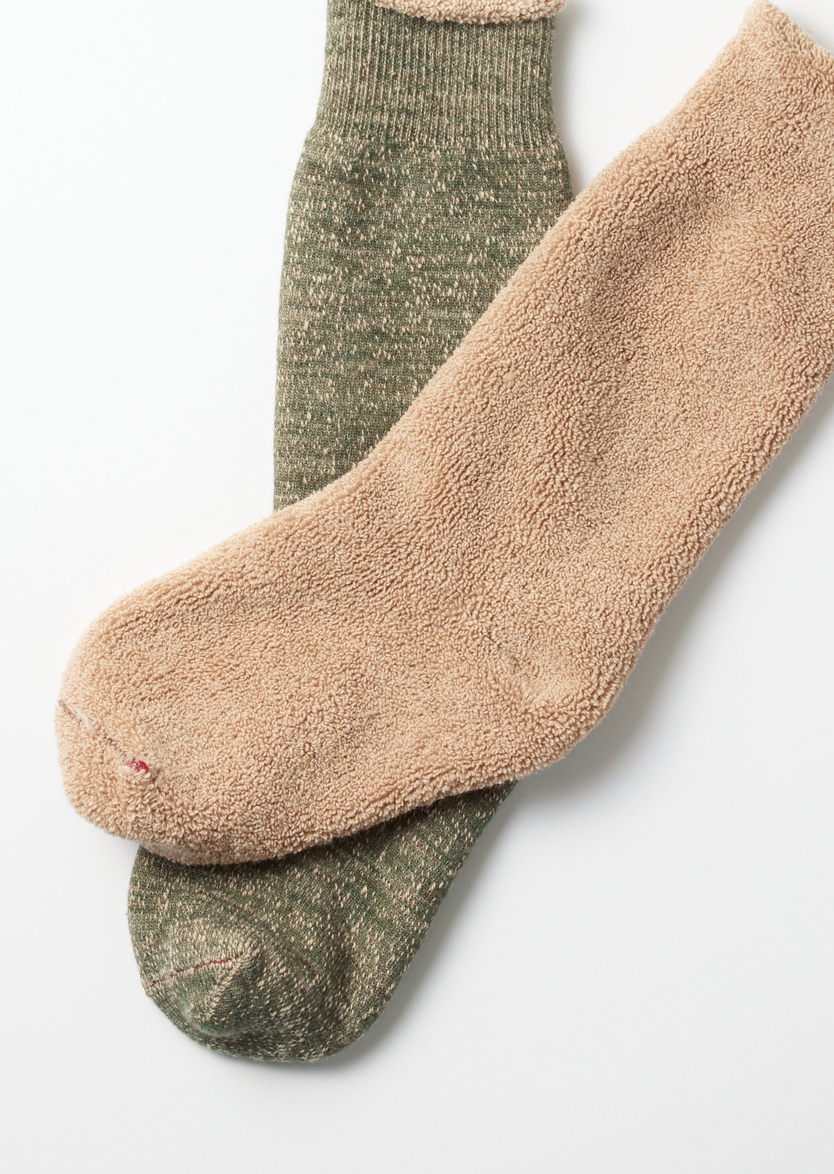 Close-up of two pairs of textured crew socks, one tan and one olive green, laid flat.