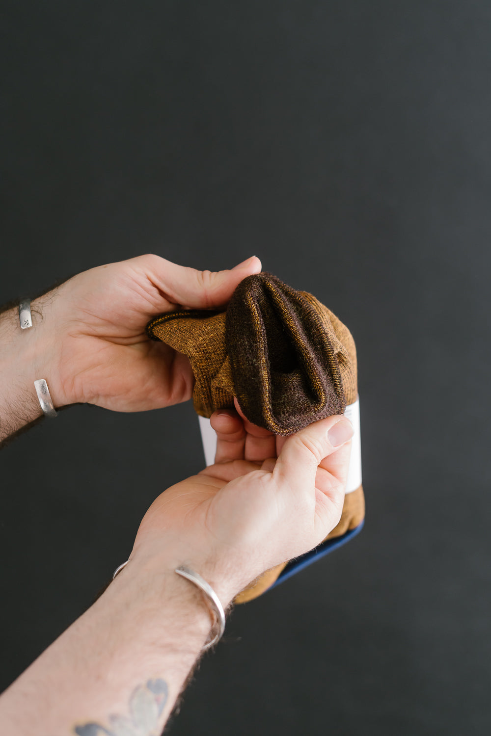 Close-up of hand holding yellow-brown RoToTo City Crew Socks, showing fabric texture, toe area