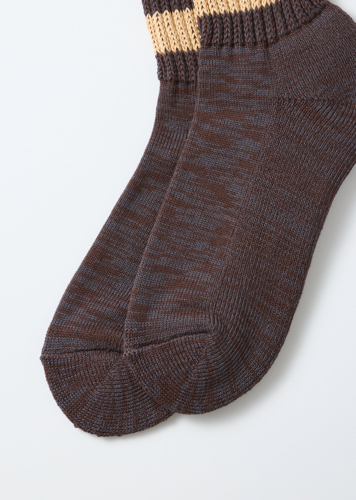 Close-up front view of textured brown knit socks with tan patterned cuffs.