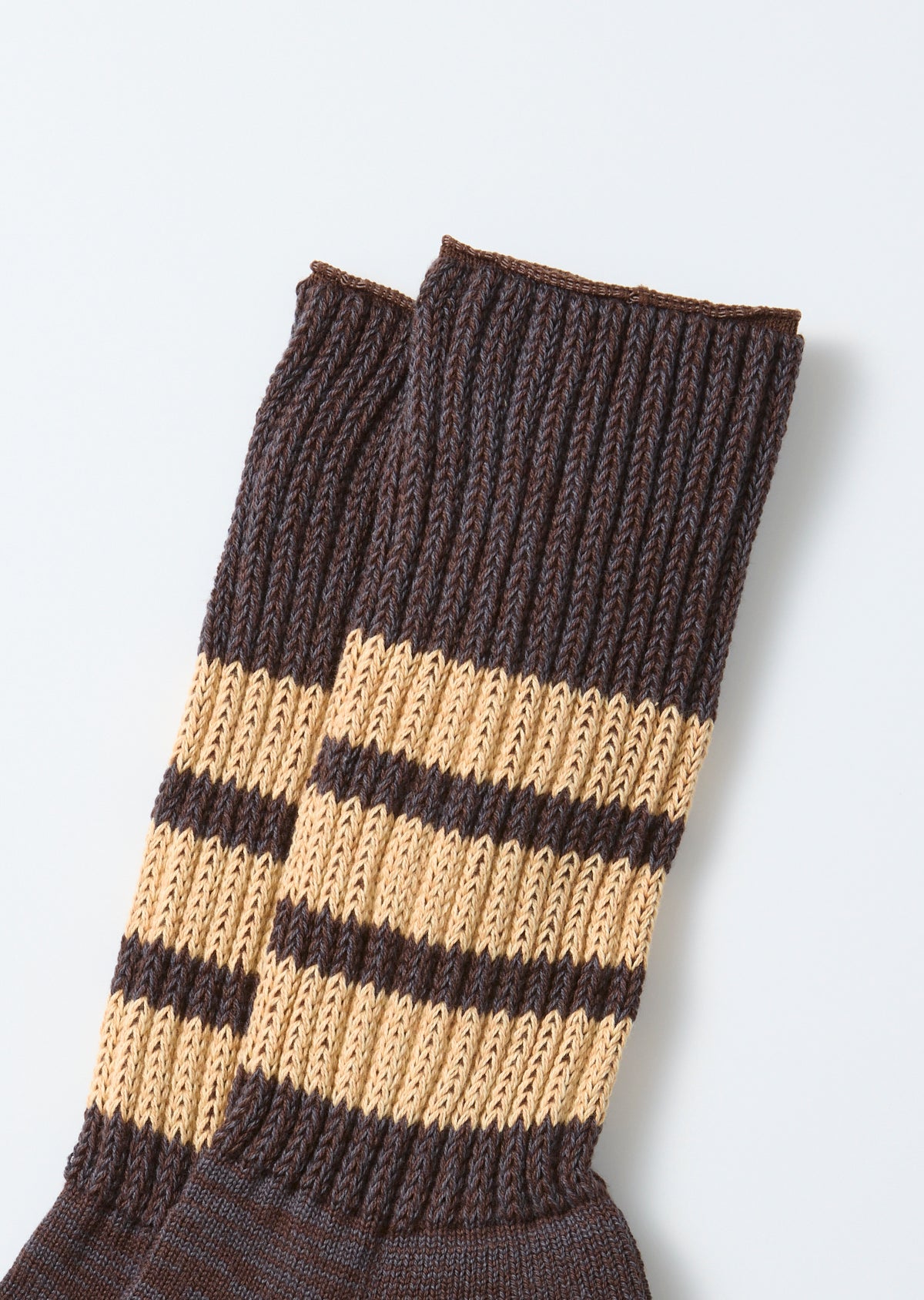 Flat lay front view of ribbed knit crew socks in brown with tan horizontal stripes.