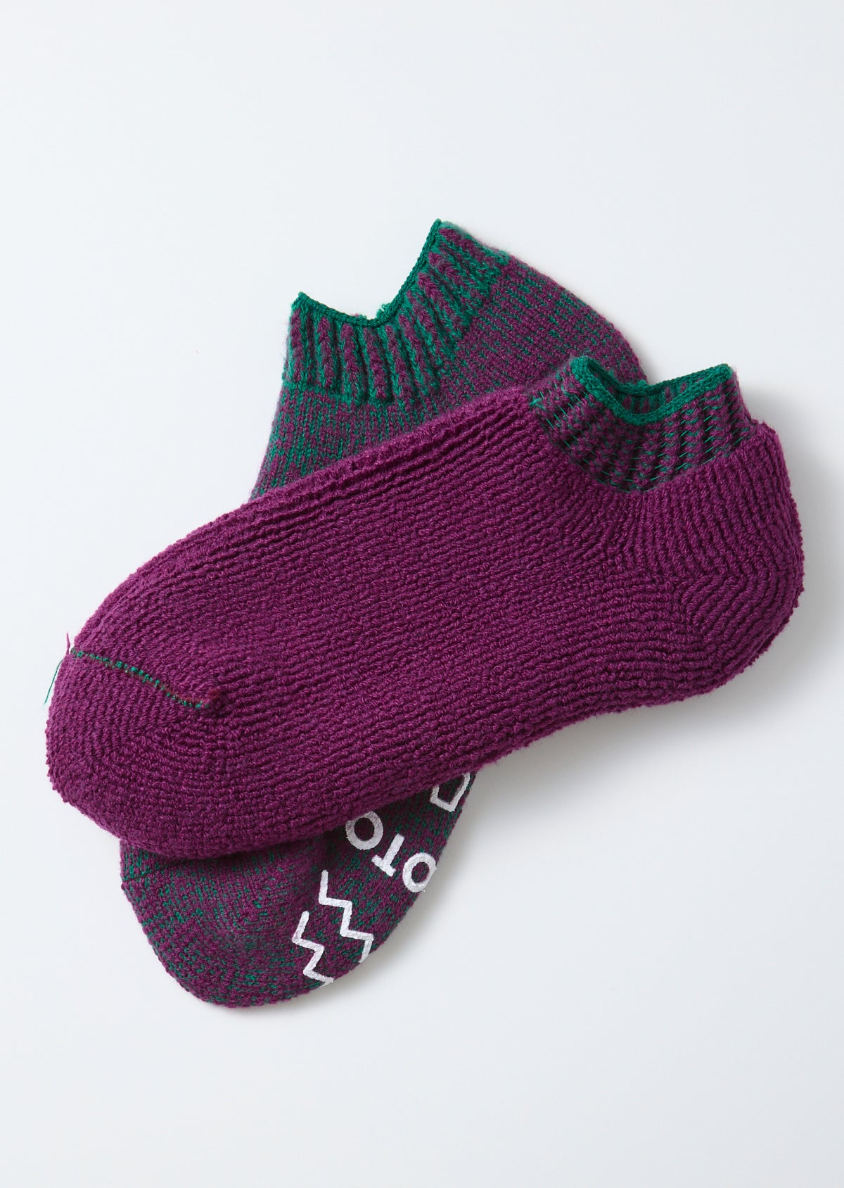 Flat lay close-up of purple knit socks with green accents, showing front and top views.
