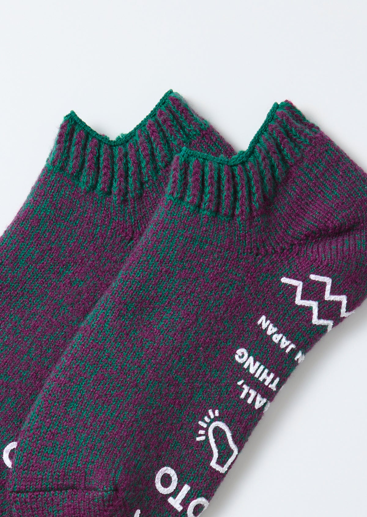 Close-up of the side view showing the knit texture and graphic pattern on purple and green socks.