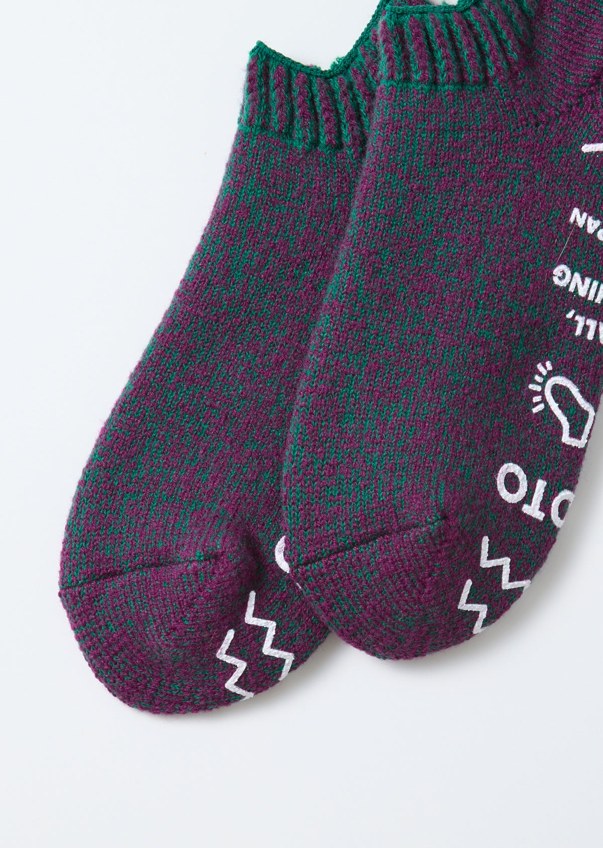 Close-up flat lay of the front of purple and green marled knit socks with white graphics.