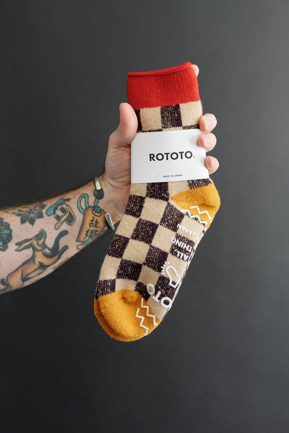 Close-up of a hand holding a patterned Rototo sock showing the side view.