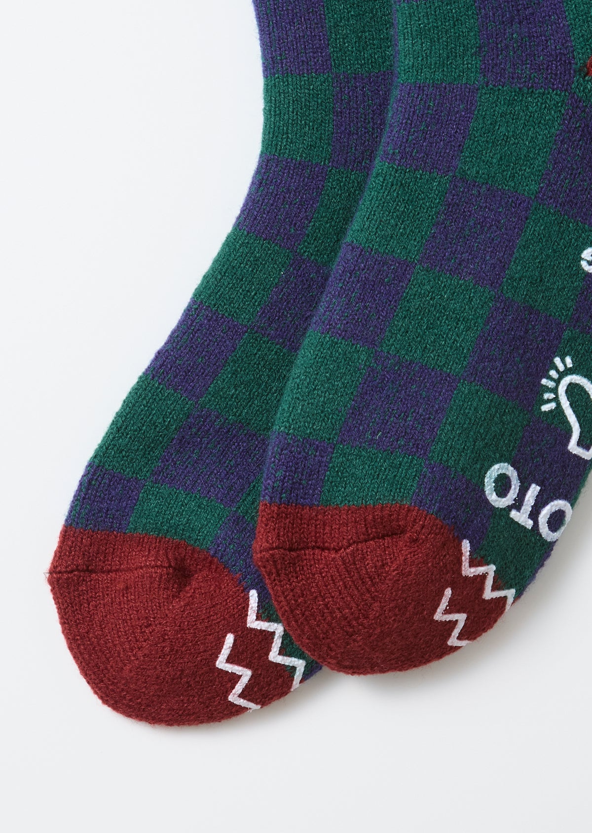 Close-up of the toe area showing the front of green and purple checkered socks with red heels and white patterns.