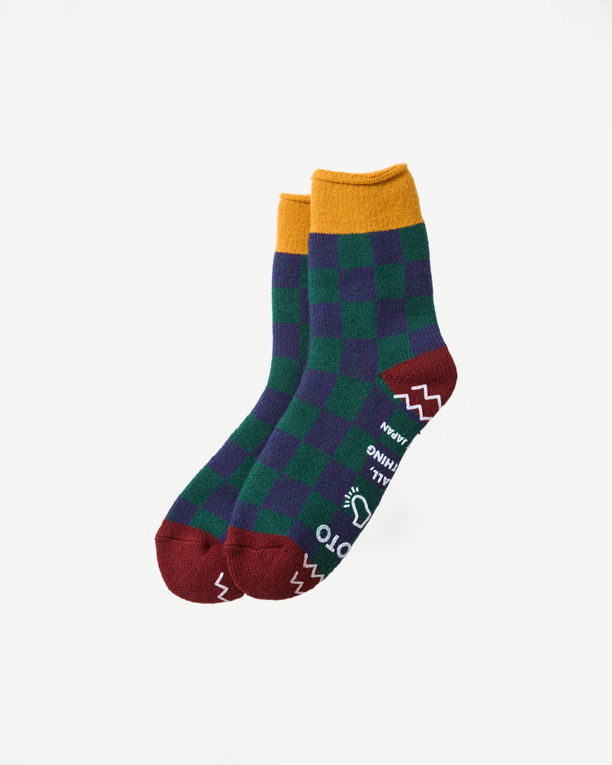 Close-up flat lay of the front of checkered green and purple socks with yellow cuffs.
