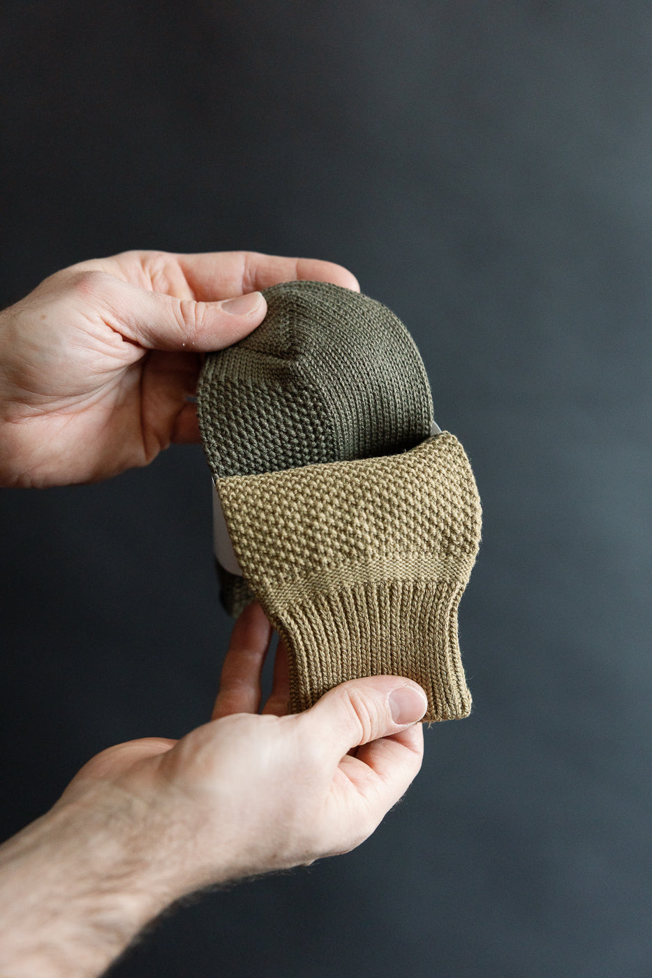 Close-up of Rototo seed stitch socks in dark olive shown flat, highlighting texture and ribbed cuff.