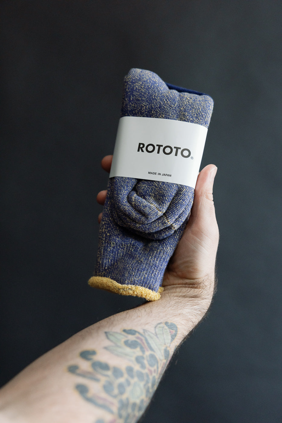 Close-up of Rototo reversible pile socks in blue and light yellow, front flat lay, in hand.