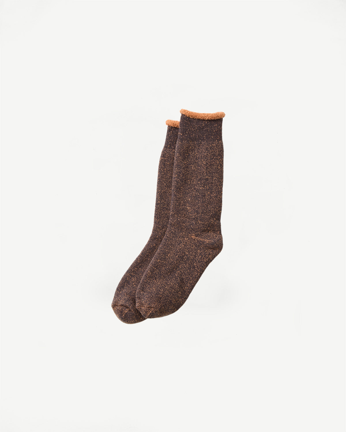 Flat lay, front view of Rototo reversible pile socks in faded black and light orange, textured knit.