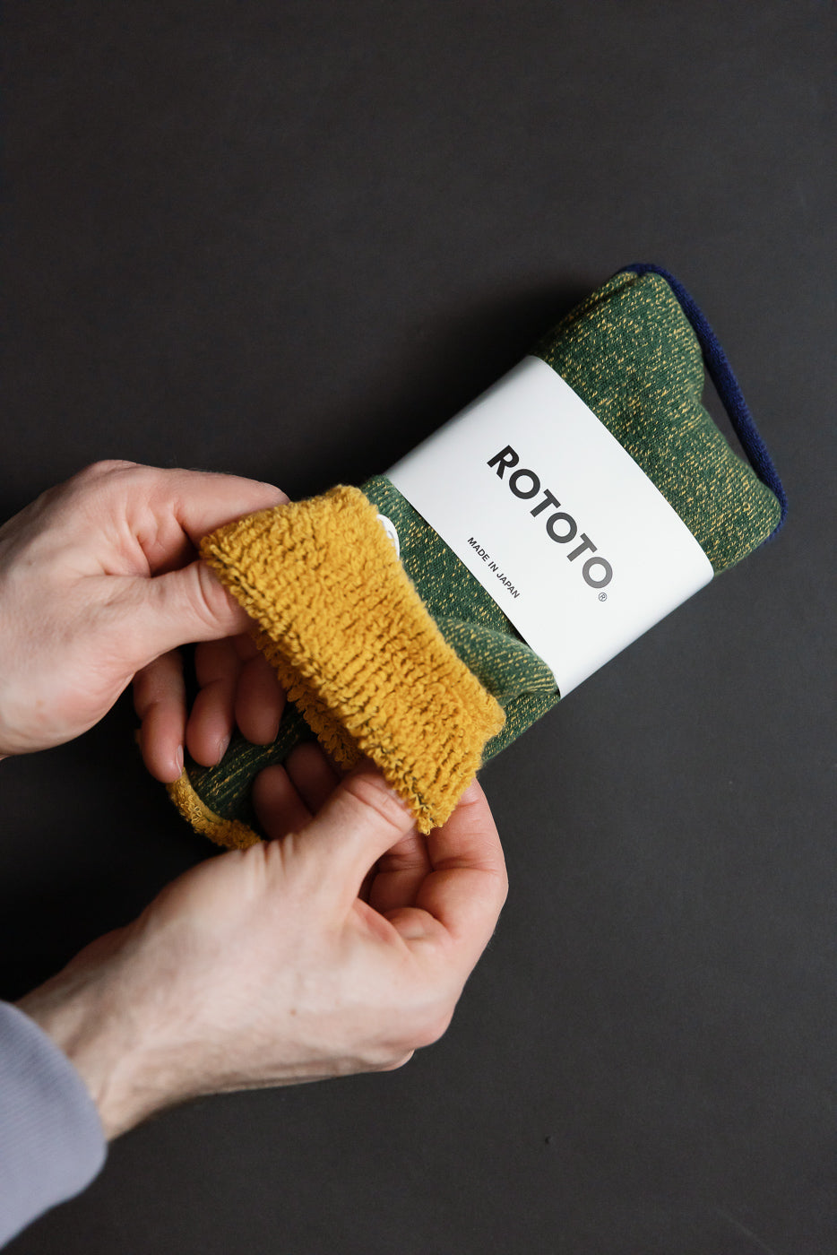R1612 - Reversible Pile Socks - Ivy Green, Dark Yellow are shown with a white paper band labeled “ROTOTO – Made in Japan.” Hands reveal the mustard-yellow terry-loop lining, highlighting their reversible design.