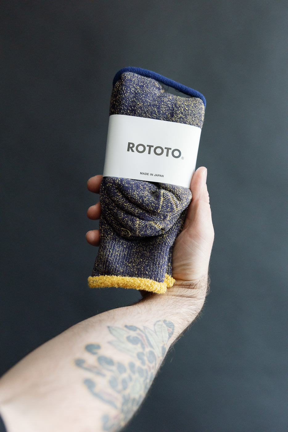 Close-up of Rototo reversible pile socks navy/yellow front, product held in hand, Dant shop