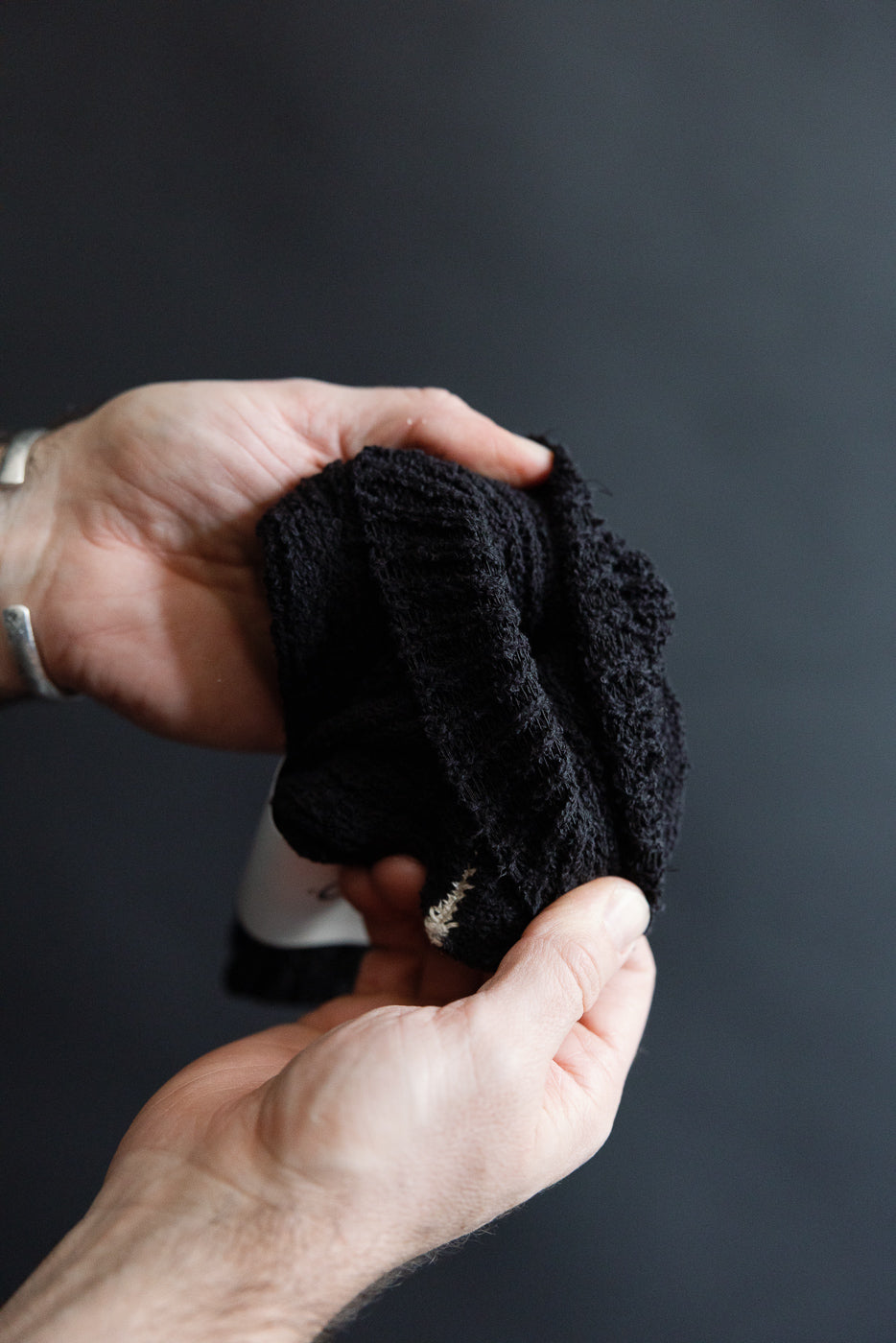 Close-up of hand holding Rototo recycled cotton boucle crew socks in black, texture detail visible.