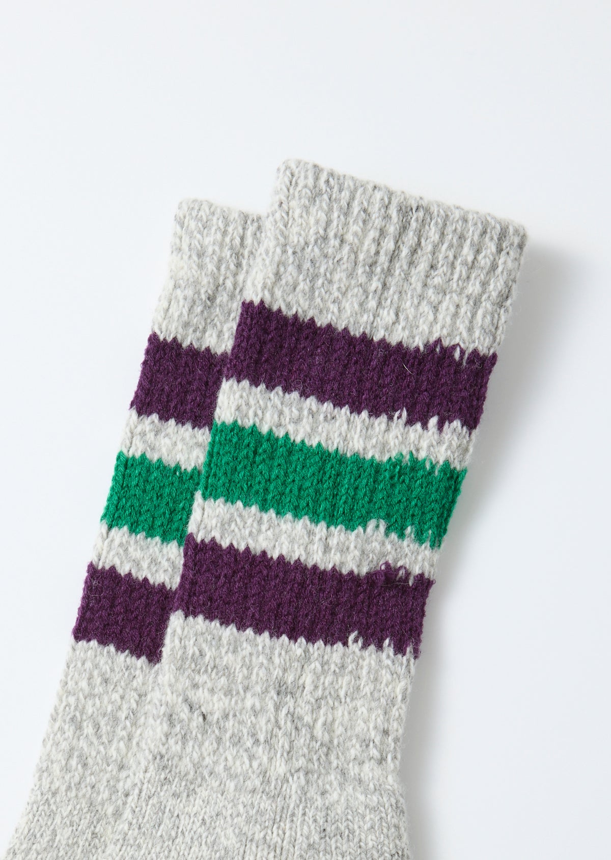 Close-up of the front of grey knit socks with purple and green stripes.