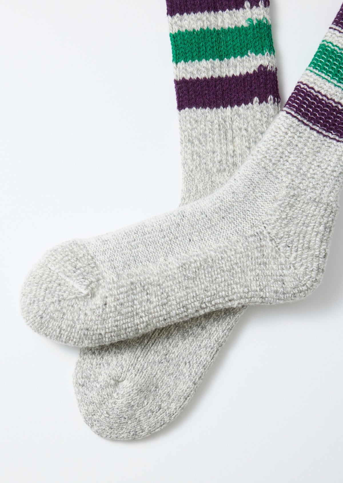 Close-up flat lay of grey knit socks with purple and green stripes, showing fabric texture.