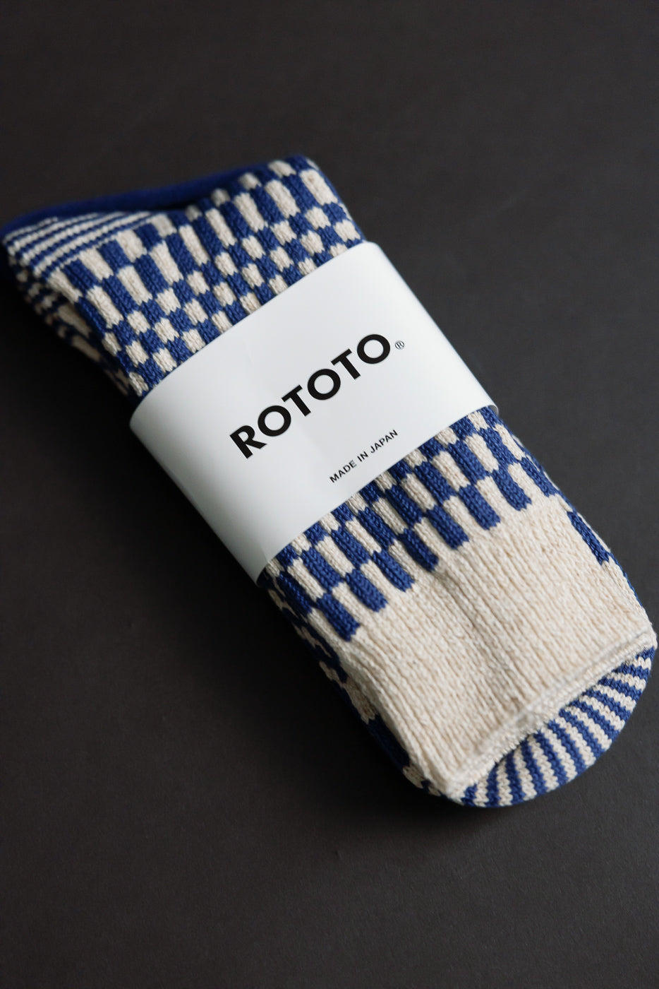 Close-up flat lay of blue and cream checkerboard crew socks, front side, showing knit texture and packaging.