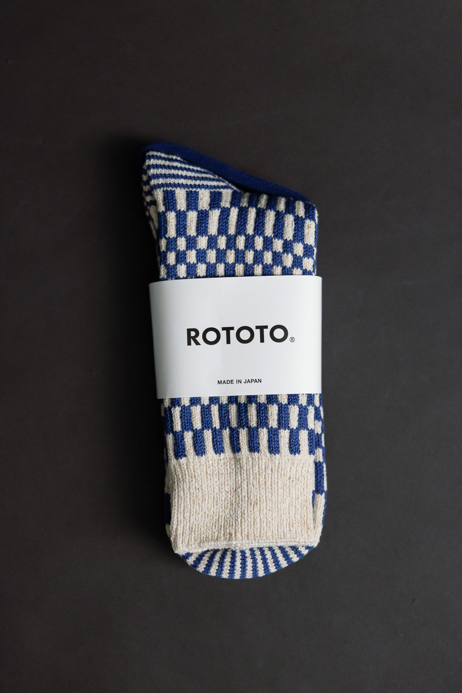 Close-up of front side of folded blue and beige checkerboard crew socks, visible label details.
