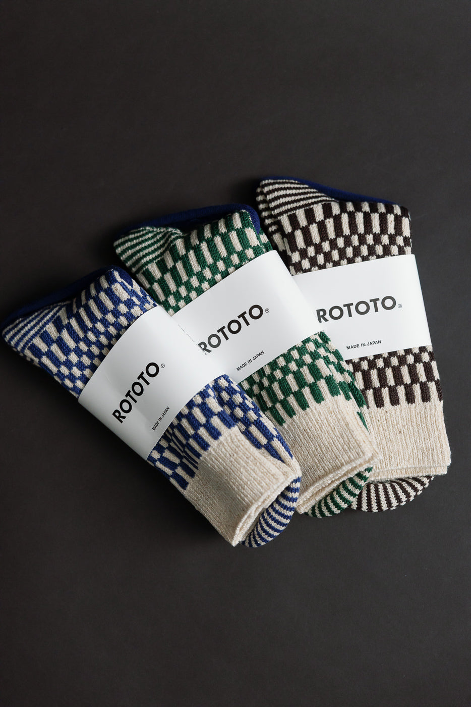 Flat lay of three pairs of crew socks in blue, green, and brown checkerboard pattern, front view.