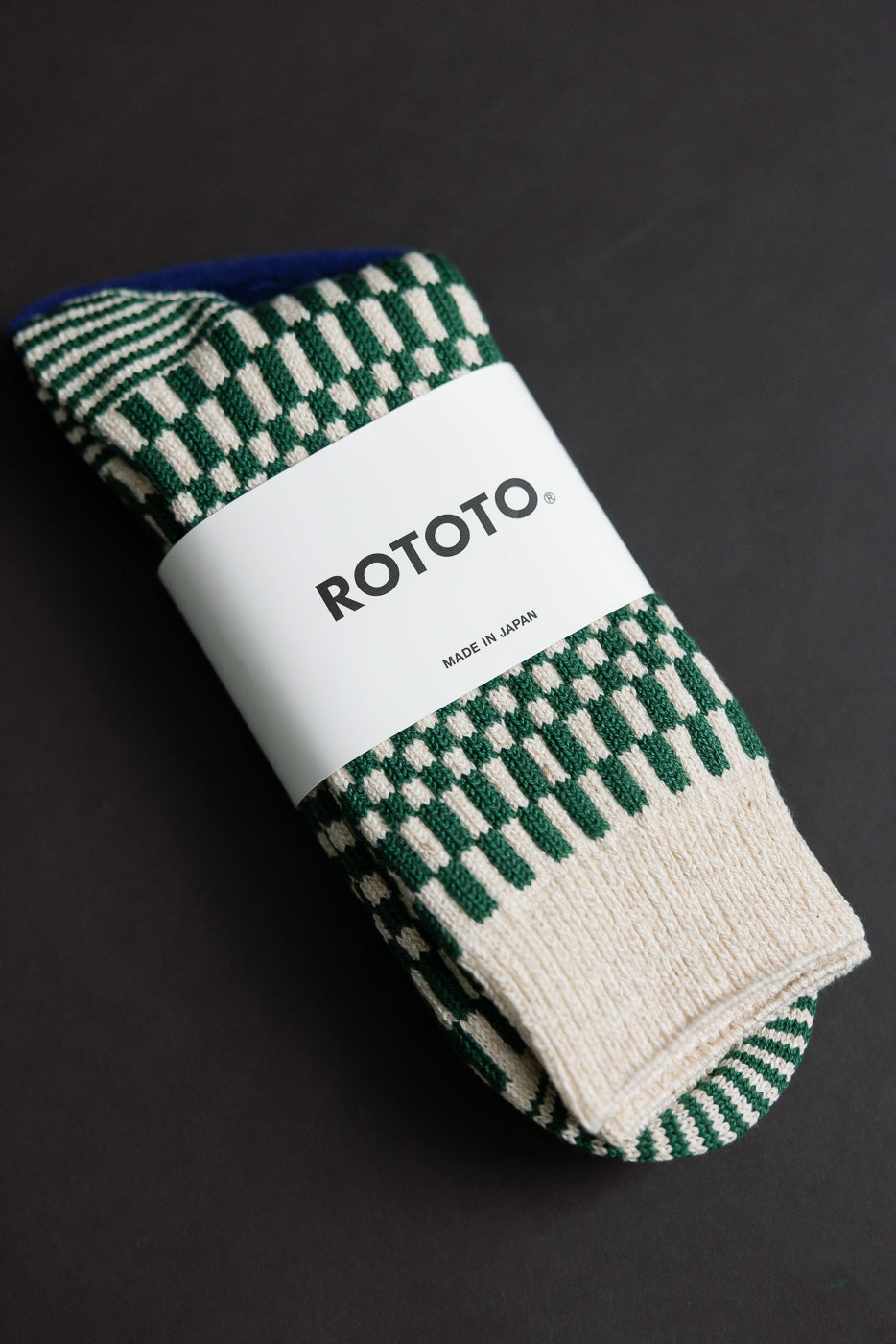 R1621 - Checkerboard Pattern Crew Socks - Green, featuring a green-and-cream geometric design, wrapped in a ROTOTO band. Crafted in Japan, these moderate-thickness socks are jacquard-knitted for a smooth, sleek fit.