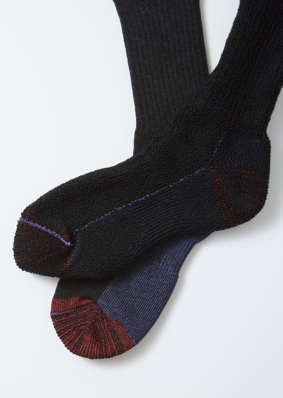 Close-up flat lay of the front of black ribbed socks with a navy and burgundy heathered toe.