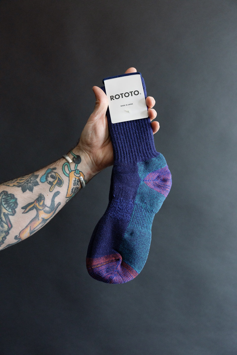 Close-up of a hand holding Rototo double face merino pile sock, dark blue, front side, Dant store