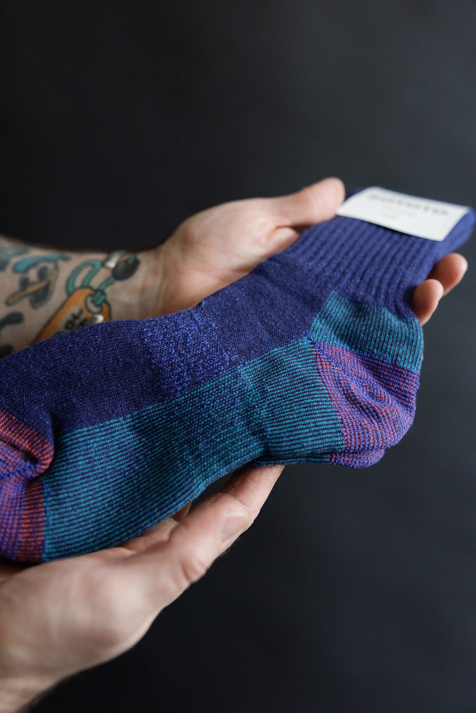 Close-up of Rototo R1632 double face merino pile sock, dark blue with colorblock heel, showing fabric texture held in hand.