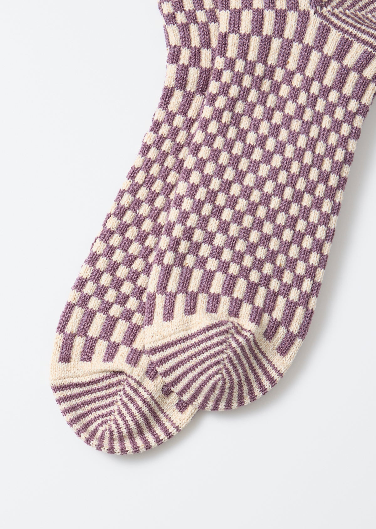 Flat lay close-up of the front side of purple and cream checkered patterned knit socks.
