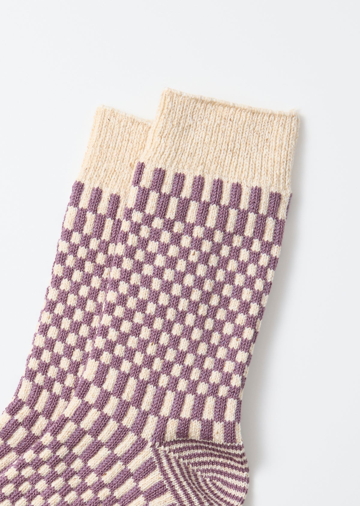 Close-up of the front side of cream and purple checkered patterned socks.