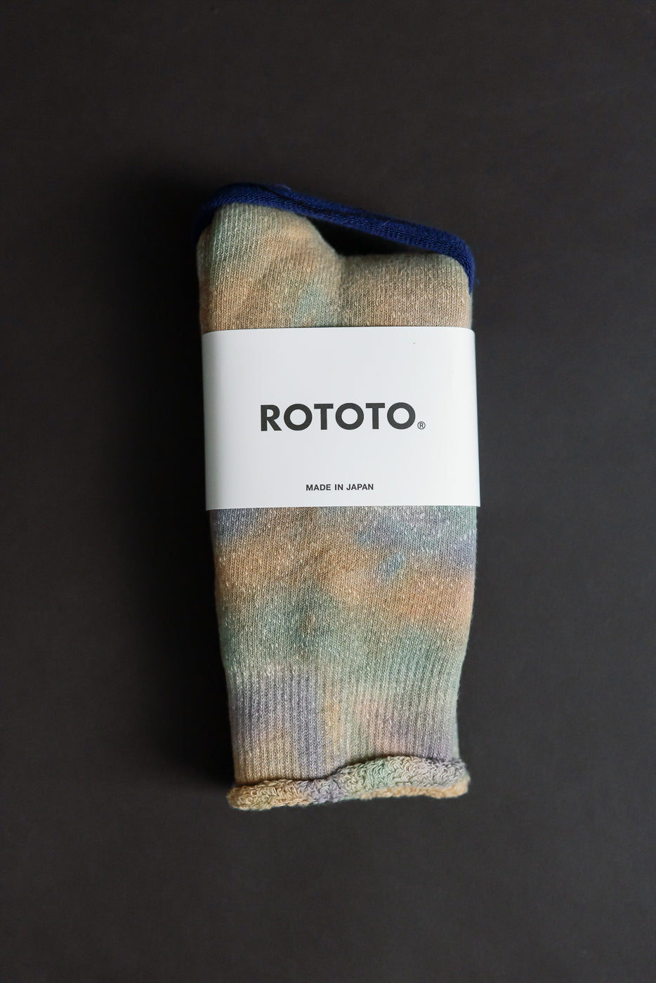 Flat lay close-up of front side of tie-dye crew socks in green, light pink, purple with label