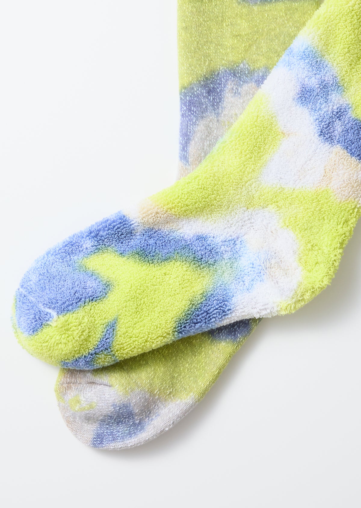 Close-up of front side of tie-dye crew socks in green, lime, and blue showing plush pile texture.