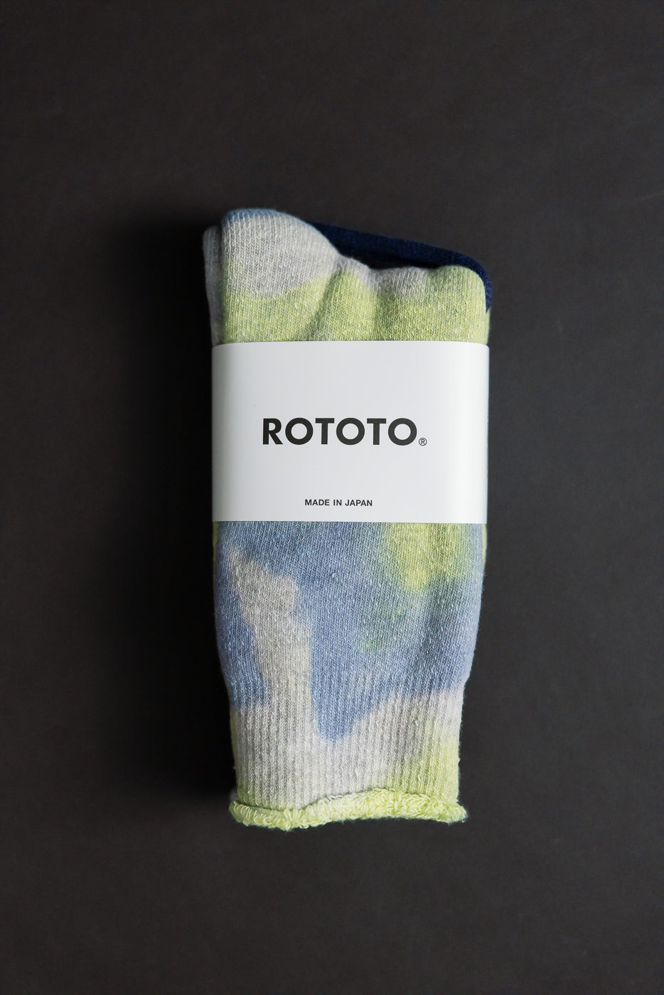 Flat lay close-up of front side tie-dye crew socks in green, lime, and blue with tag visible.