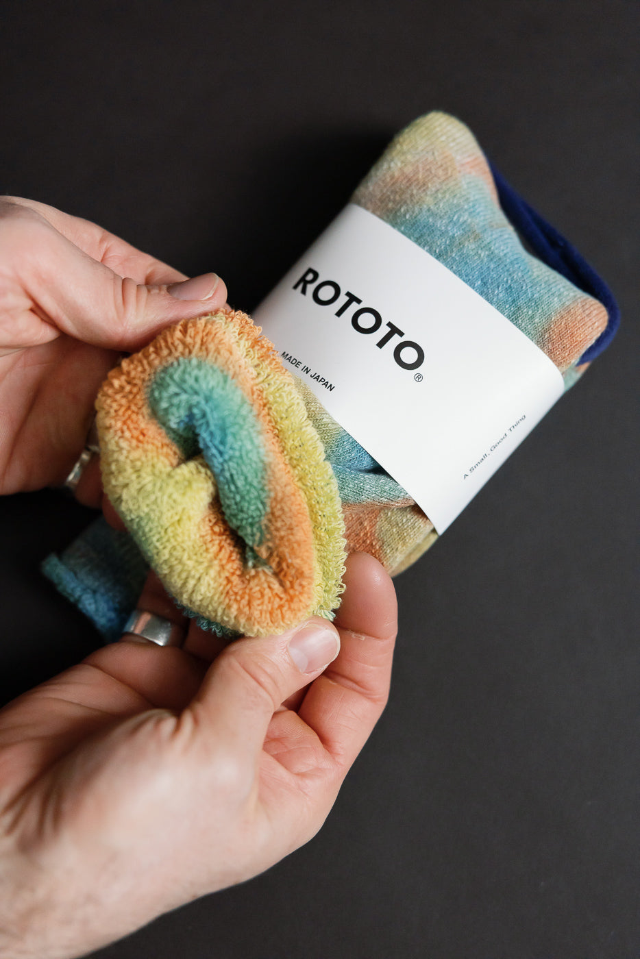 Close-up of hands holding tie-dye crew socks, showing soft pile fabric texture, top view.