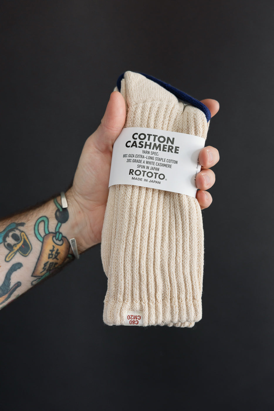 Close-up front view of cream cotton cashmere ribbed socks held in hand.