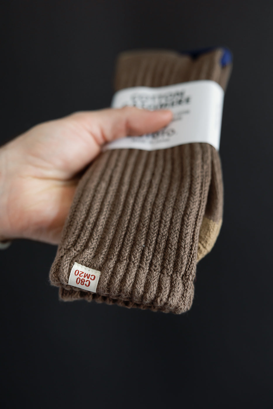 Close-up of the ribbed texture and CM20 tag on brown cotton knit socks.