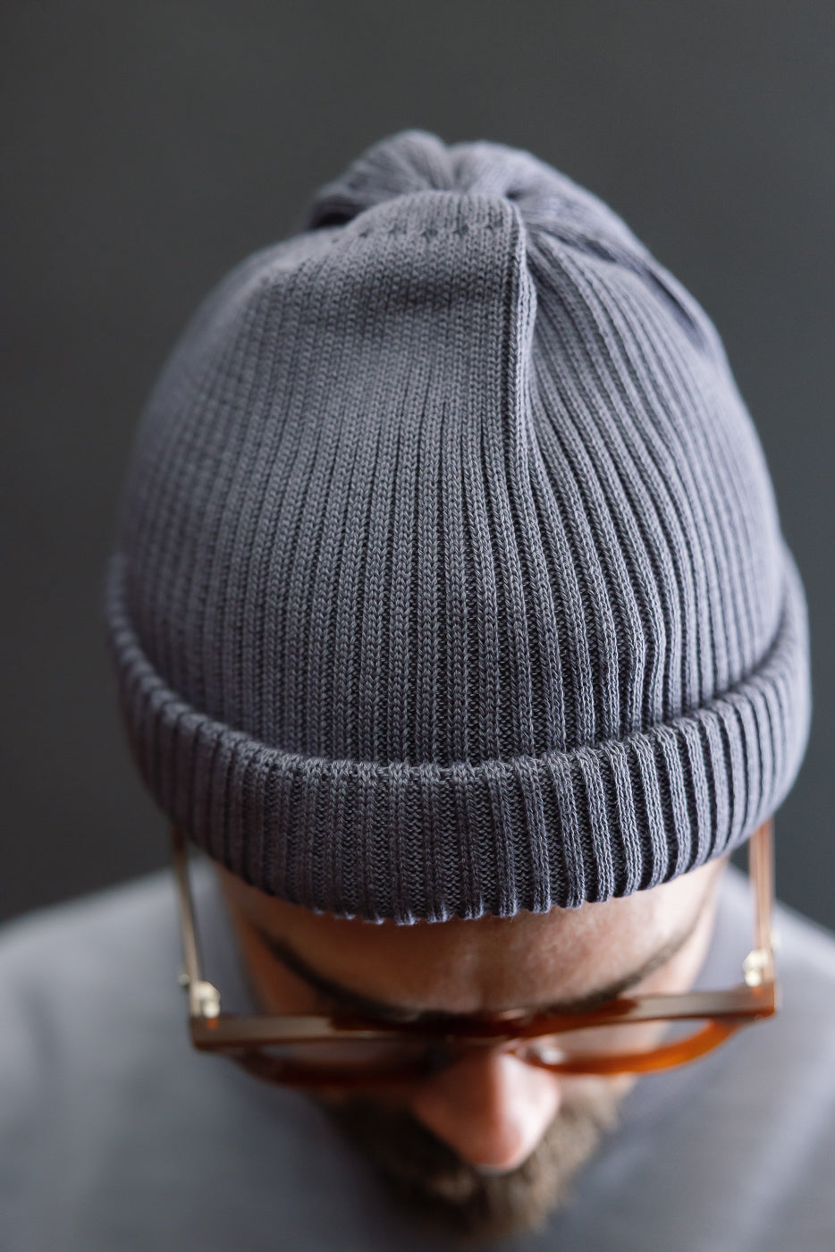 Close-up of front of ribbed faded blue cotton roll-up beanie on male model, top detail shown.