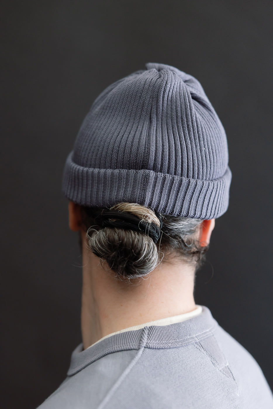 Rear close-up of faded blue cotton roll-up beanie on male model, 5'9