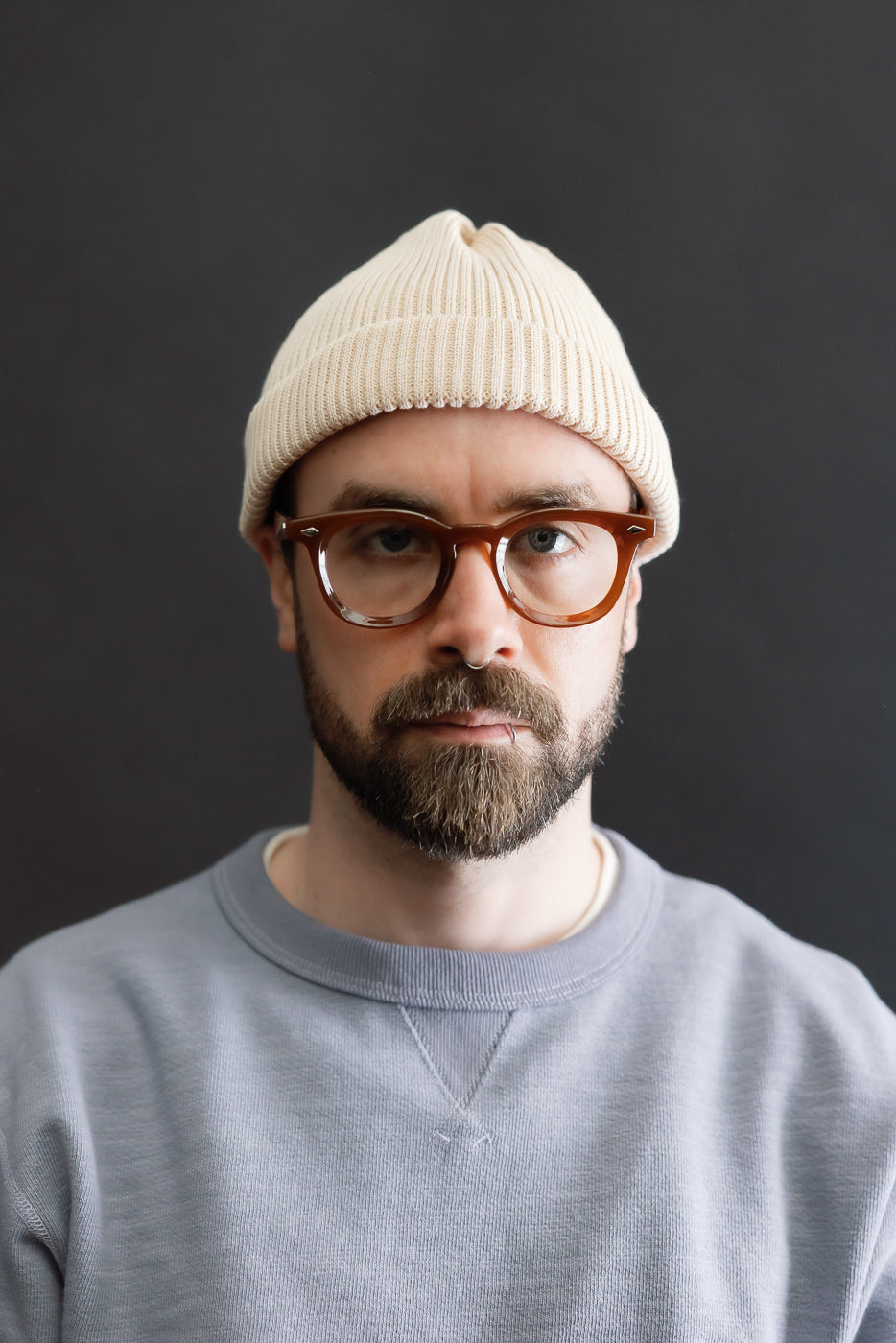 Front close-up of cotton roll-up beanie in raw beige on male model, 5'9