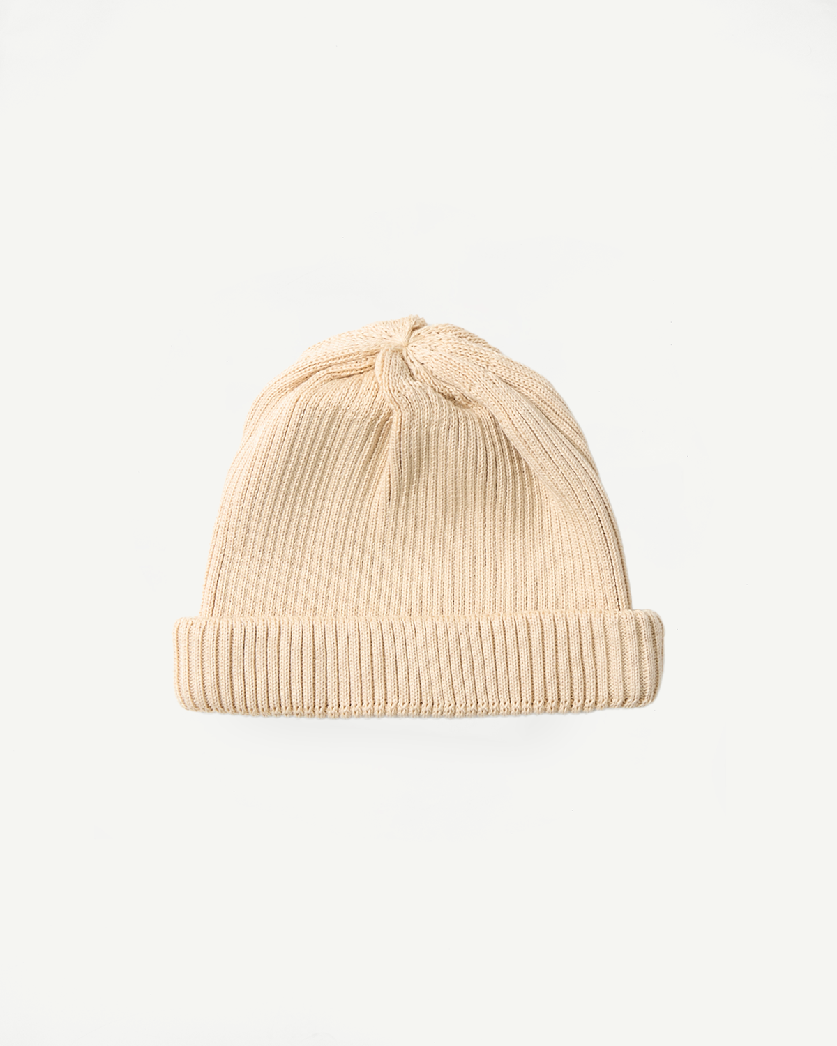 Front flat lay of raw beige ribbed cotton roll-up beanie, showing cuff and crown details.