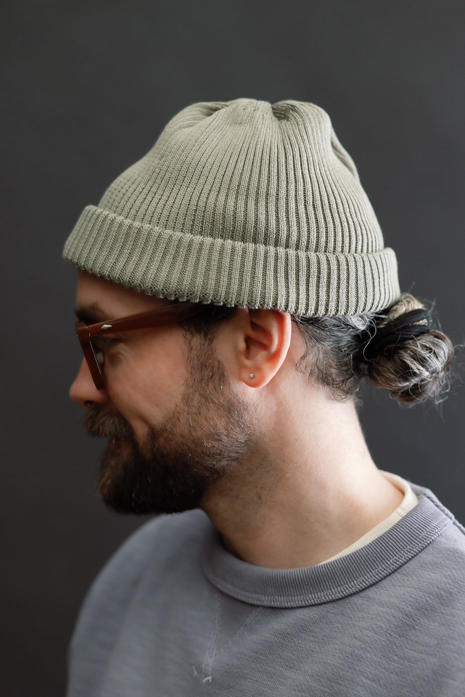Side close-up of sage cotton roll-up beanie on male model, 5'9
